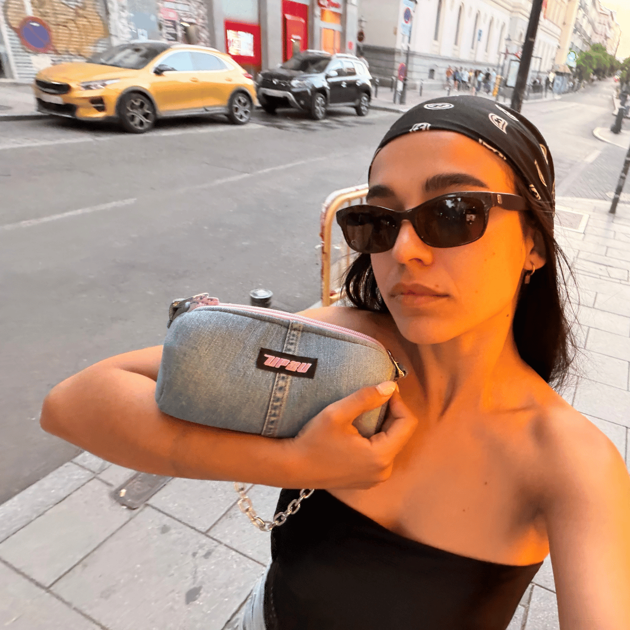 Modelo mostrando la UP2U Jeans Mini Bag de denim upcycled en exterior urbano al atardecer